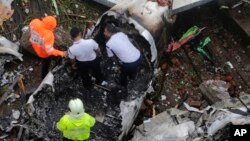 FILE: Rescuers stand amid the wreckage of a private chartered plane that crashed.