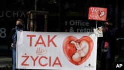 Anti-abortion activists hold a protest in front of Poland's Constitutional Court, in Warsaw, Poland, Oct. 22, 2020. The signs read "Yes to Life" in Polish.