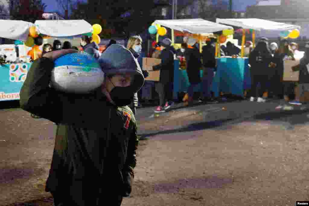 A boy carries a turkey distributed by La Colaborativa, a non-profit group that gave out free groceries for 3,500 people, ahead of the Thanksgiving holiday, in Chelsea, Massachusetts, Nov. 23, 2021.