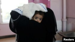 A woman carries a child at the malnutrition ward of al-Sabeen hospital in Sanaa, Yemen, Sept.11, 2018. 