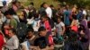 Migrantes esperan ser procesados por la Patrulla Fronteriza y de Aduanas de EEUU después de cruzar el Río Grande y entrar a EEUU desde México, el 19 de octubre de 2023, en Eagle Pass, Texas. 