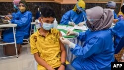 A teenager receives the Sinovac COVID-19 coronavirus vaccine in Pekanbaru, Riau, on July 9, 2021, as part of a mass vaccination program including children. (Photo by WAHYUDI / AFP)