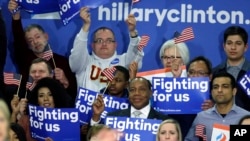 FILE - Supporters of Democratic presidential candidate Hillary Clinton hold signs and flags, March 22, 2016, during a campaign rally at Rainier Beach High School in Seattle, Wash.