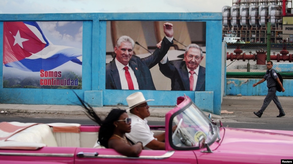 Un automóvil antiguo pasa junto a una imagen del expresidente de Cuba, Raúl Castro, y del presidente y primer secretario del Partido Comunista de Cuba, Miguel Díaz-Canel, junto a un cartel que dice: "Somos continuidad", en La Habana, Cuba, el 17 de abril de 2023.