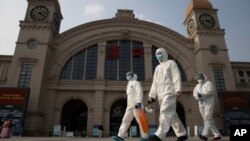 Trabajadores con trajes protectores pasan por la estación de tren de Hankou en vísperas de su reanudación del tráfico saliente en Wuhan, en el centro de Hubei, el 7 de abril de 2020.