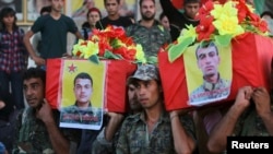 FILE - Members of the Kurdish People's Protection Units (YPG) carry coffins of their fellow fighters, who were killed during clashes with Islamic State fighters on the Iraqi-Syrian border, during their funeral in Ras al-Ain city, in Syria's Hasakah provin