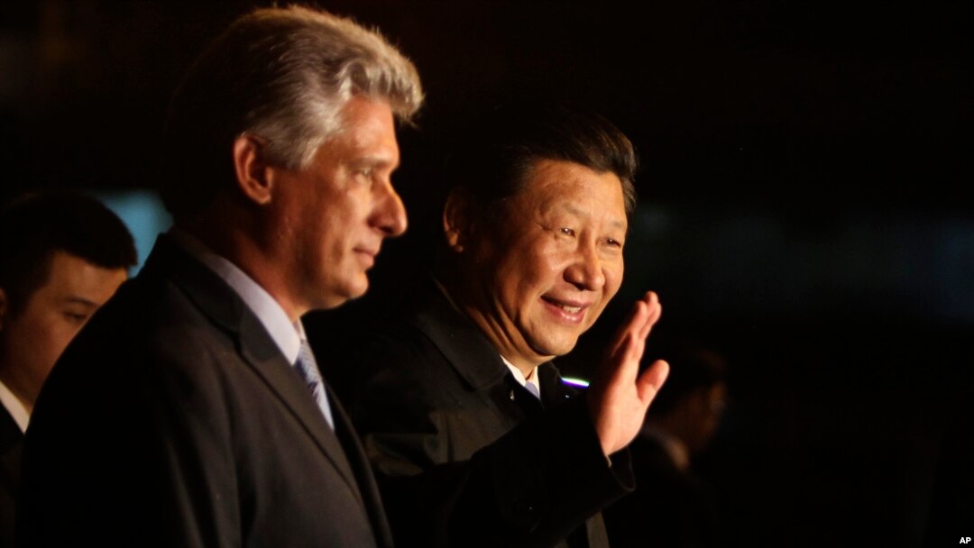 China's President Xi Jinping, center, waves to the press accompanied by Cuba's Vice President Miguel Diaz-Canel, left, at his arrival at the Jose Marti International Airport in Havana, Cuba, July 21, 2014.