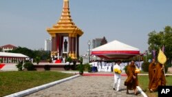 Cambodia's Buddhist monks, right, walk around during an opening of the inauguration of a statue of Cambodia's late King Norodom Sihanouk, in front of Independence Monument in Phnom Penh, Cambodia, Friday, Oct. 11, 2013. Cambodia has inaugurated a large monument honoring the country’s former king, nearly a year after his death. (AP Photo/Heng Sinith)