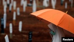 Seorang perempuan mengenakan masker dan pelindung wajah berdoa saat pemakaman seorang kerabat di pemakaman khusus jenazah pasien Covid-19 di TPU Pondok Rangon, Jakarta, 24 September 2020. (Foto: Reuters)