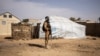 FILE - A Burkina Faso soldier patrols at a camp sheltering internally displaced people from northern Burkina Faso in Dori, Feb. 3, 2020. Attackers have massacred at least 160 people in the northern village of Solhan overnight Friday.