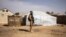 FILE - A Burkina Faso soldier patrols at a camp sheltering internally displaced people from northern Burkina Faso in Dori, Feb. 3, 2020. Attackers have massacred at least 160 people in the northern village of Solhan overnight Friday.