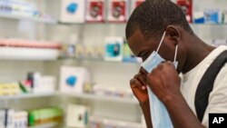 In this Feb. 6, 2020, photo, a man tries on a face mask at a pharmacy in Kitwe, Zambia.