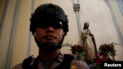 Seorang polisi di dalam Gereja Katedral Jakarta untuk memeriksa keamanan menjelang perayaan natal, Jakarta, 24 Desember 2016. (Foto:Dok)