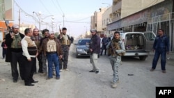 Armed tribesmen and Iraqi police stand guard in a street as clashes rage on in the Iraqi city of Ramadi, West of Baghdad, on January 2, 2014.