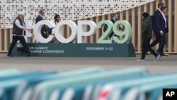 与会者走过会场外的COP29联合国气候高峰会标志。(美联社：2024年11月23日)