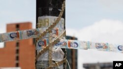 ARCHIVO - En esta foto de archivo del 20 de julio de 2017, los billetes y monedas de banco de Bolívar devaluados, pegados con cinta adhesiva, sirven como cuerda improvisada en una barricada establecida por manifestantes antigubernamentales en Caracas, Venezuela. El gobierno venezolano presentó a la Asamblea Constituyente el jueves 2 de agosto de 2018 un decreto que volvería a legalizar todas las operaciones en casas de cambio. (Foto AP / Ariana Cubillos, Archivo)