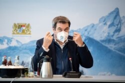 FILE - Bavaria's State Prime Minister Markus Soeder removes his protective mask before a so-called home office summit during the coronavirus pandemic in Munich, Germany, Jan. 13, 2021.