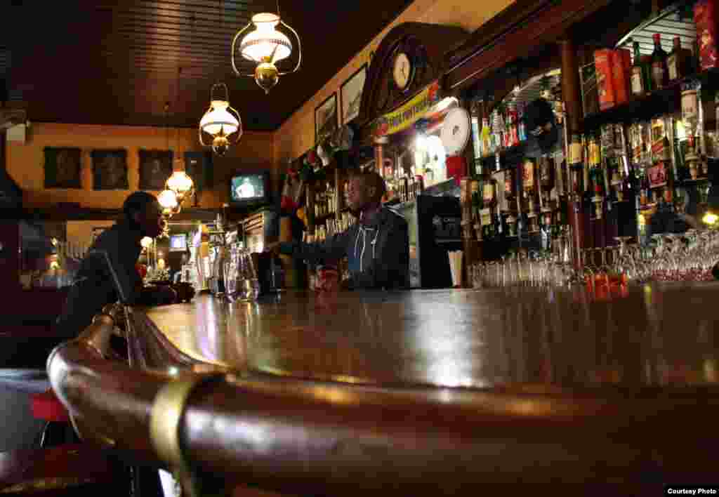 Decades of regulars put a sheen on the wood and brass bar where Thokozane Nxumalo serves clients of The Guildhall, Johannesburg&#39;s oldest bar.&nbsp;​Photo by Darren Taylor