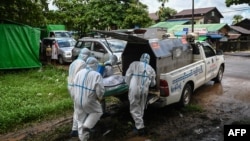 Volunteers wearing personal protective equipment (PPE) prepare to transport the body of a victim of the Covid-19 coronavirus to a cemetery in Hlegu Township in Yangon on July 10, 2021. (Photo by Ye Aung THU / AFP)