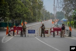 Tentara paramiliter India dan seorang polisi berjaga di jalan yang ditutup menjelang kunjungan Perdana Menteri India Narendra Modi ke Srinagar, wilayah Kashmir yang dikuasai India, Kamis, 19 September 2024. (Mukhtar Khan/AP)