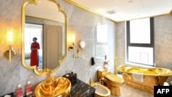 Un membre du personnel pose pour une photographie à l'intérieur de la suite exécutive de deux chambres à coucher de 1000 dollars par nuit du nouvel hôtel Dolce Hanoi Golden Lake, le premier hôtel plaqué or au monde, à Hanoi le 2 juillet 2020.