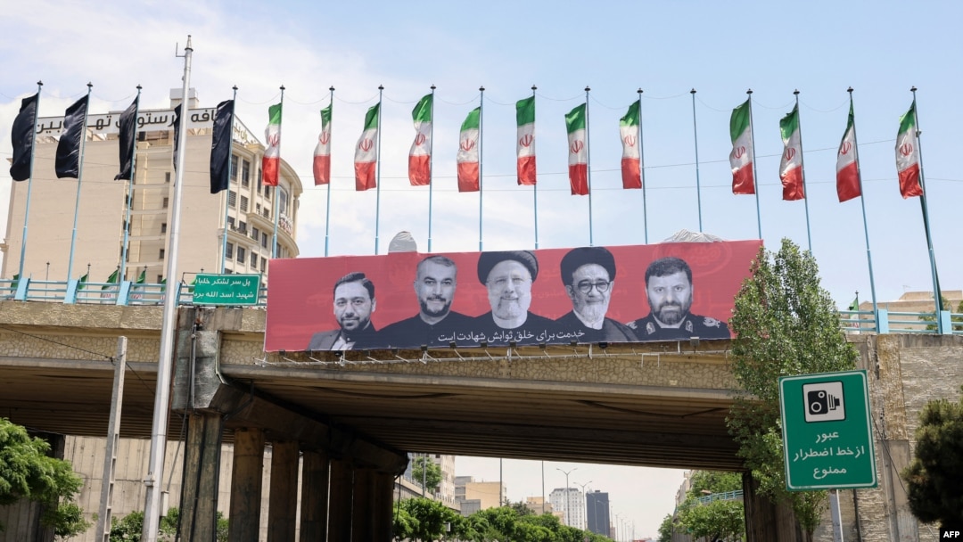 Cars drive past a billboard bearing a portrait of Iran's late president Ebrahim Raisi, center, his foreign minister Hossein Amirabdollahian, second from left, and other members of his entourage in central Tehran, on May 21, 2024.