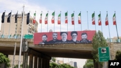Cars drive past a billboard bearing a portrait of Iran's late president Ebrahim Raisi, center, his foreign minister Hossein Amirabdollahian, second from left, and other members of his entourage in central Tehran, on May 21, 2024.