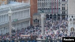 FILE - People walk on Saint Mark's Square in Venice, Italy, June 9, 2019. 