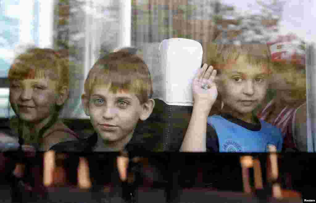 Refugee children from eastern Ukraine look out the window of a mini-bus upon their arrival at a railway station, in Stavropol, southern Russia, Aug. 21, 2014.