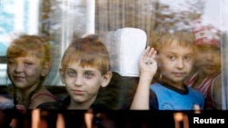 FILE - Children who have fled the fighting in eastern regions of Ukraine look out from a minibus upon their arrival at a railway station, before leaving for their temporary accommodation, in Stavropol, southern Russia, Aug. 21, 2014. 
