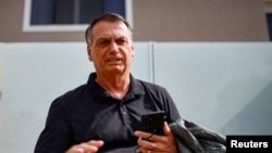 FILE - Former Brazilian President Jair Bolsonaro stands in front of his house before testifying to the federal police in Brasilia, Feb. 22, 2024. Judicial papers released March 15 say Bolsonaro presented military leaders with a plan to reverse the 2022 election if he lost. 