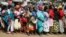 FILE - Women queue for a planned distribution of food for those suffering from the impact of the coronavirus pandemic, at a site in the Kibera slum of Nairobi, Kenya, April 10, 2020.