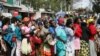 FILE - Women queue for a planned distribution of food for those suffering from the impact of the coronavirus pandemic, at a site in the Kibera slum of Nairobi, Kenya, April 10, 2020.