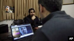 Farhad Azima, Iranian director and screenwriter of the animated film "Battle of the Persian Gulf II" (center) gives an interview, while a man watches a trailer for the movie, at his office, in Tehran, Iran, Feb. 26, 2017.