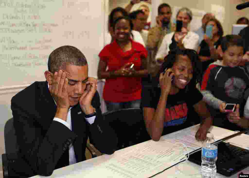 U.S. President Barack Obama talks with volunteers on a mobile phone in his campaign field office in Orlando, Florida, October 28, 2012.