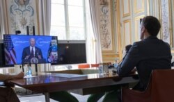 French President Emmanuel Macron listens to U.S. President Joe Biden speaks during a Climate Summit video conference, at the Elysee Palace, in Paris, April, 22, 2021.