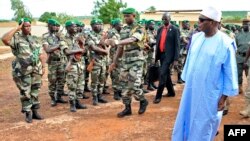 Mali's President Ibrahim Boubacar Keita, right, reviews troops in Kati, near Bamako, after visiting soldiers injured in an attack on their camp in northern Mali earlier in the week that left 11 other soldiers dead, Aug. 6, 2015.