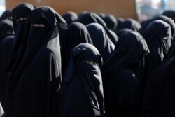 FILE - Women stand together al-Hol displacement camp in northeastern Syria, April 2, 2019.