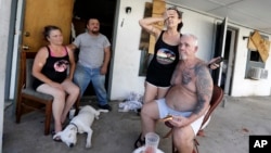 Debra Harmon holds her head as she recall riding out Hurricane Harvey in their apartment they lack of resources they have available including electricity, Aug. 29, 2017, in Aransas Pass, Texas. 