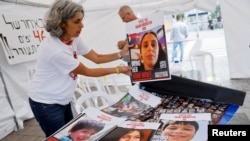 Simpatizantes de las familias de rehenes tomados por Hamás en Israel preparan carteles con las fotos de los capturados en Tel Aviv, el 21 de noviembre de 2023.