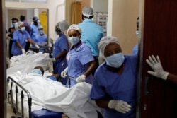 FILE - Medical staff members wait to transfer mock coronavirus patients during an exercise simulating treatment of a large number of patients because of the spread of COVID-19 at Aga Khan University Hospital in Nairobi, April 9, 2020.