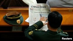 FILE - A military delegate reads a China Daily newspaper ahead of the second plenary session of the National People's Congress (NPC) in Beijing, March 9, 2009. 