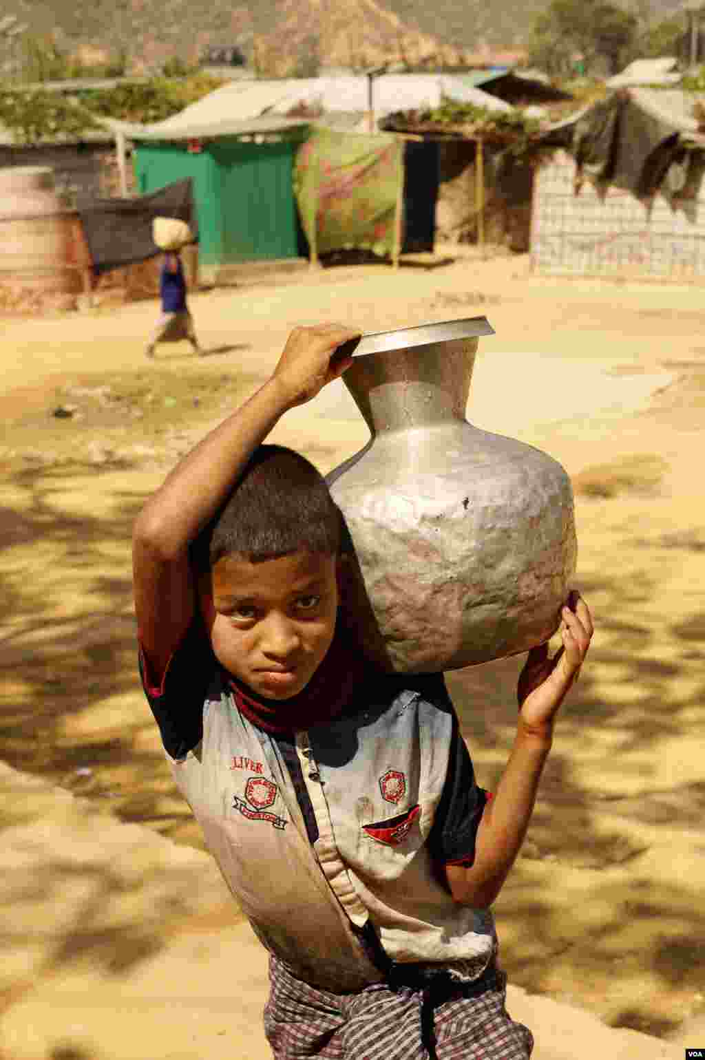 Azizul Raman, 12, carries a container of drinking water home for his family at the Rohingya refugee camp in Teknaf, Bangladesh on Feb. 12, 2020. (Hai Do/VOA)