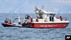 Buzos de los bomberos italianos llevan hasta un barco la bolsa con los restos mortales de una de las víctimas del naufragio del yate Bayesian, el 21 de agosto de 2024, en Porticello, cerca de Palermo, en el sur de Italia.