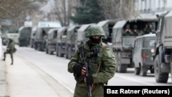 Prajurit bersenjata menunggu di kendaraan tentara Rusia di luar pos penjaga perbatasan Ukraina di Kota Krimea Balaclava, 1 Maret 2014. (Foto: REUTERS/Baz Ratner)