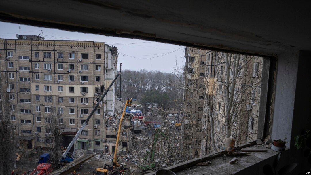 Petugas penyelamat membersihkan puing-puing dari sebuah gedung apartemen yang hancur dalam serangan roket Rusia di tenggara kota Dnipro, Ukraina, Senin, 16 Januari 2023. (AP/Evgeniy Maloletka)