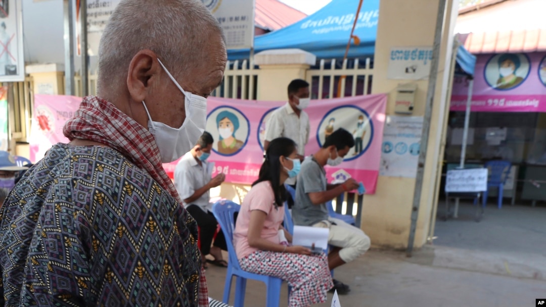 Seorang lansia (kiri), berjalan di pusat kesehatan di Phnom Penh, Kamboja, untuk suntikvaksin COVID-19 Pfizer dosis keempat, Jumat, 14 Januari 2022. (AP Photo/Heng Sinith)