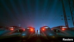 FILE - A worker stands among CRH (China Railway High-speed) Harmony bullet trains at a high-speed train maintenance base in Wuhan, Hubei province, March 9, 2015. 