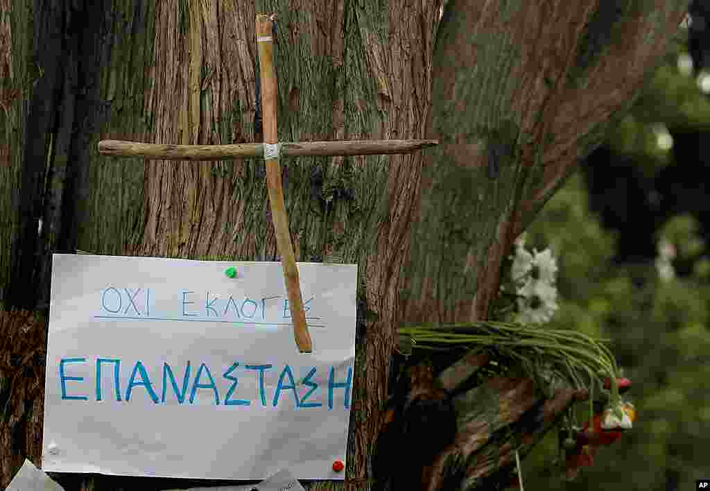 A note and a wooden cross pinned on the trunk of a tree under which an elderly man fatally shot himself at Athens' main Syntagma square, Athens, Greece, April 5, 2012.(AP) 