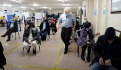 Britain's Prime Minister Boris Johnson walks past waiting patients as he visits a COVID-19 vaccination center in Batley, West Yorkshire, Britain, Feb. 1, 2021.